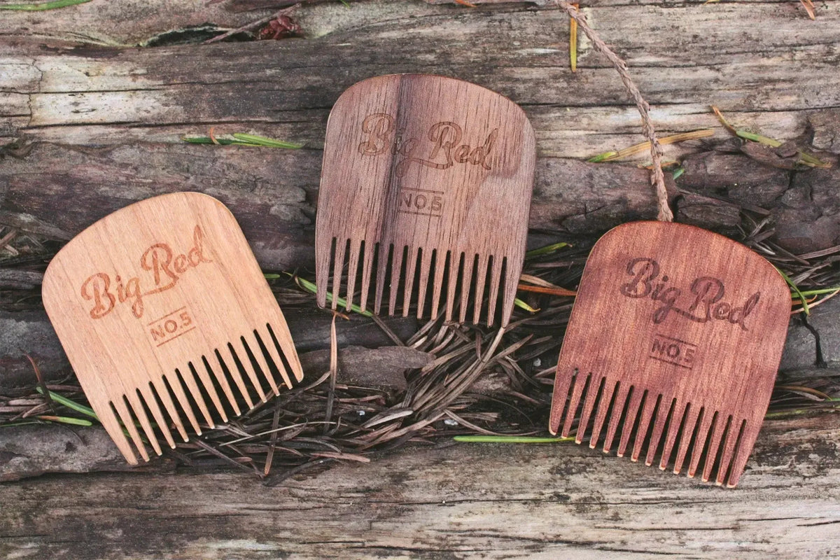 No. 5 Big Red Beard Combs in maple, walnut, and makore wood on a rustic wooden bench