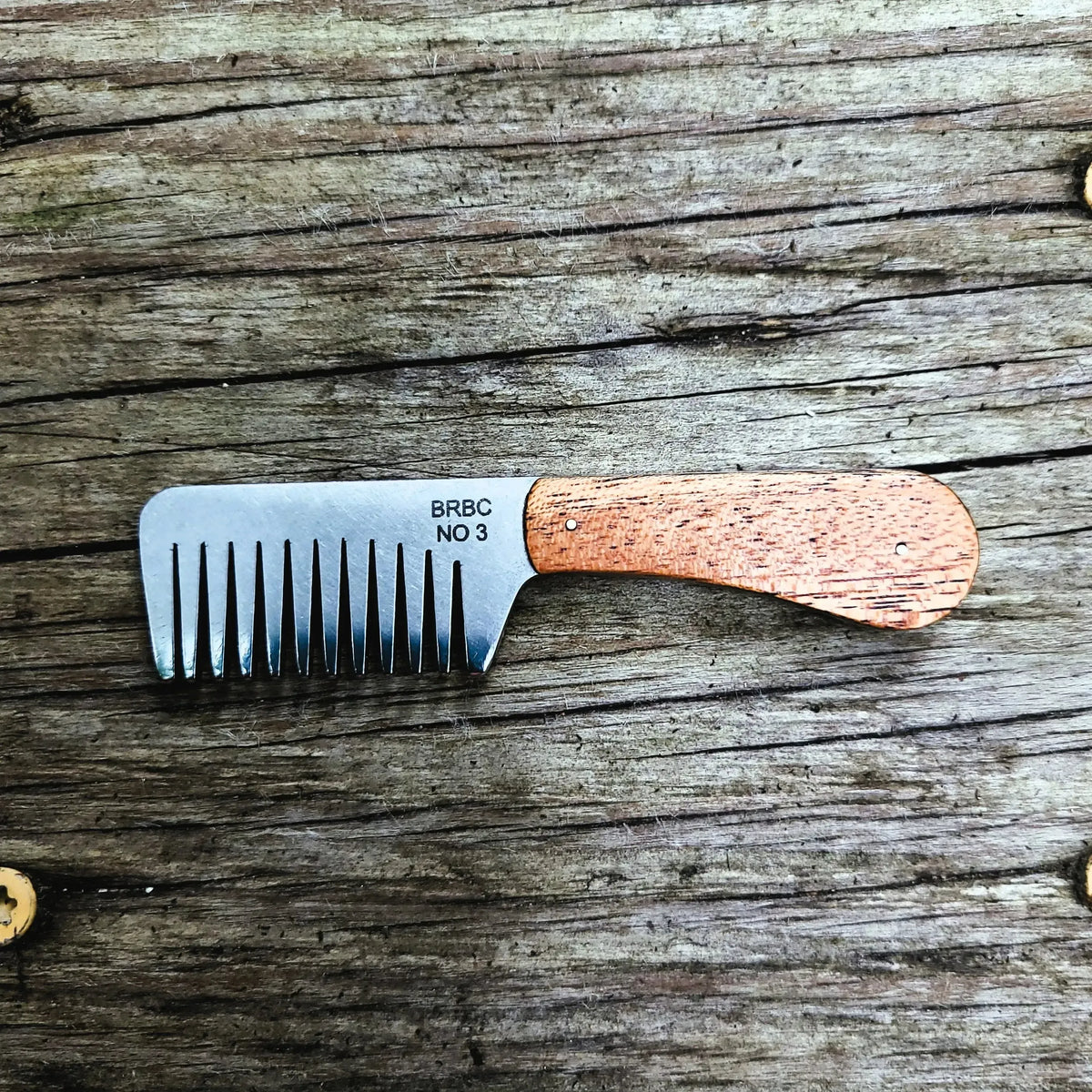 No. 3 Stainless Steel Big Red Beard Comb with mahogany handles on a wood bench