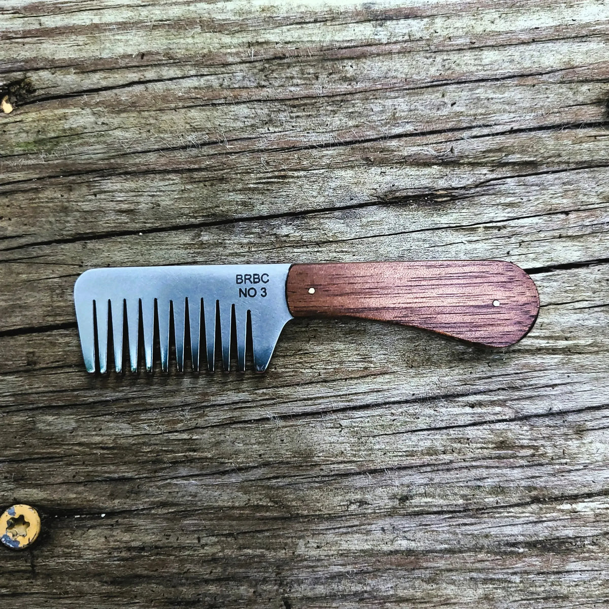 No. 3 Stainless Steel Big Red Beard Comb with walnut handles on a wood bench