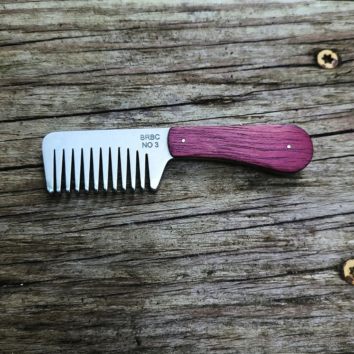 Big Red No. 3 Stainless Steel beard bomb with purpleheart handles on a wood bench
